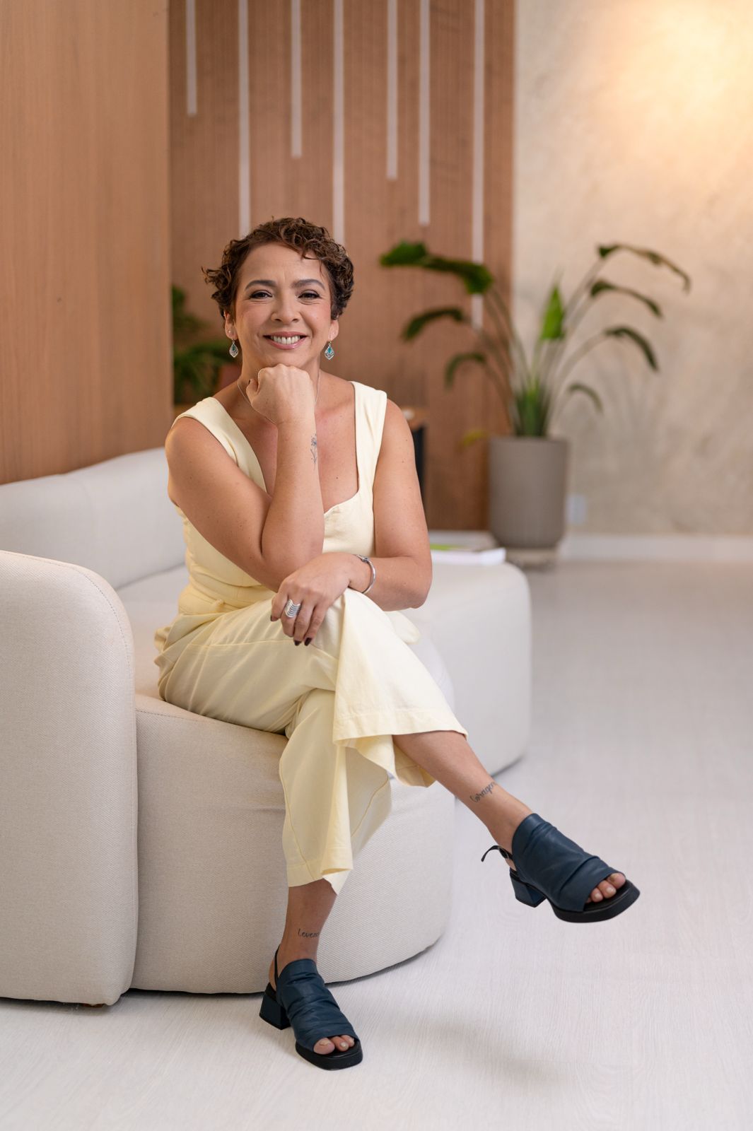 Patrícia Sena em seu consultório, sentada no sofá com postura acolhedora